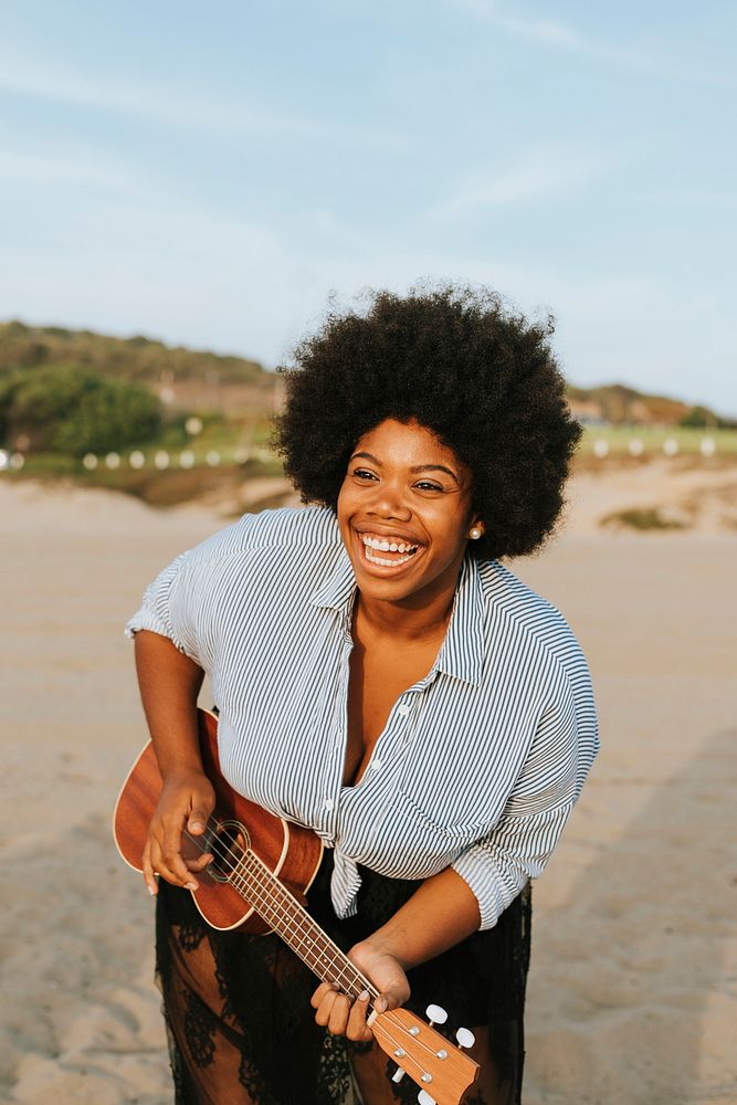 African American musician playing ukulele at the beach