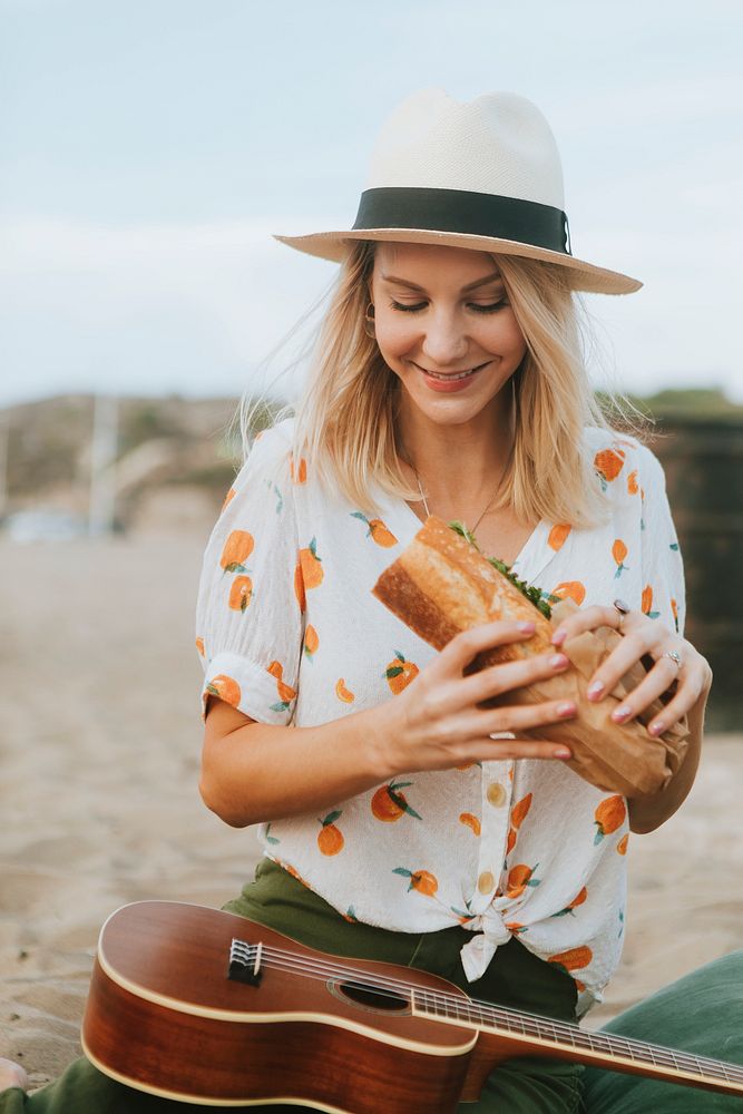 Woman eating a sandwich at a beach picnic