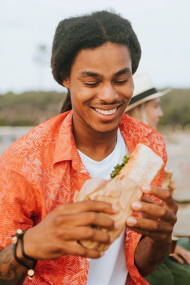 Man eating a sandwich at a beach picnic