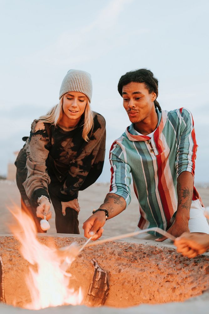 Couple roasting marshmallows over a bonfire