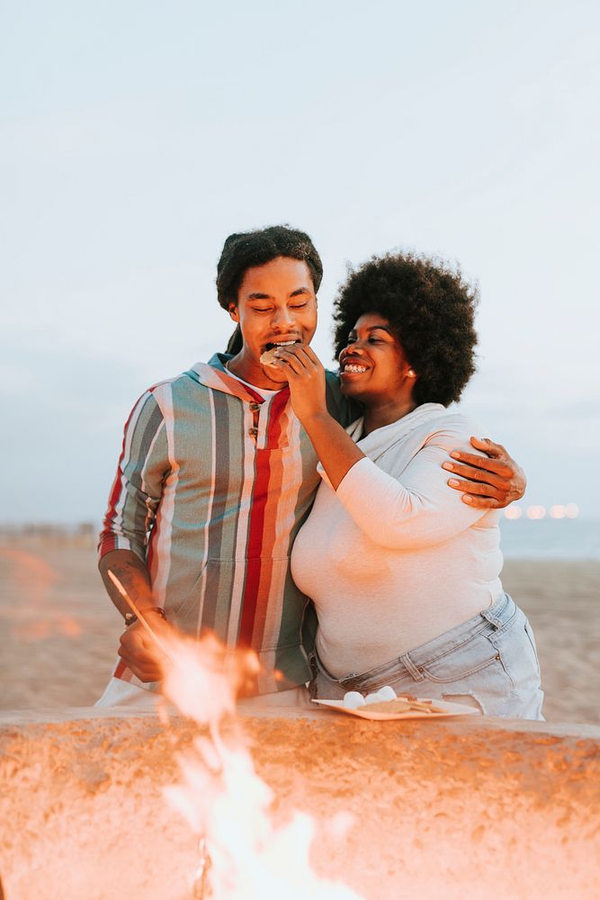 Couple making s'mores at the beach