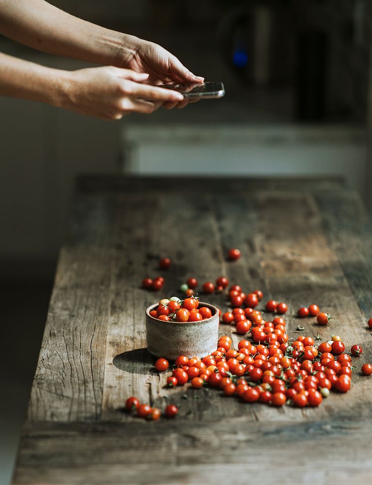 Woman taking photos of red cherry tomatoes