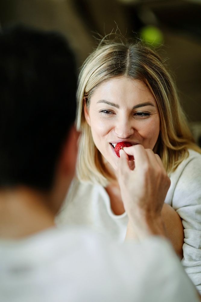 Man feeding a strawberry to his girlfriend