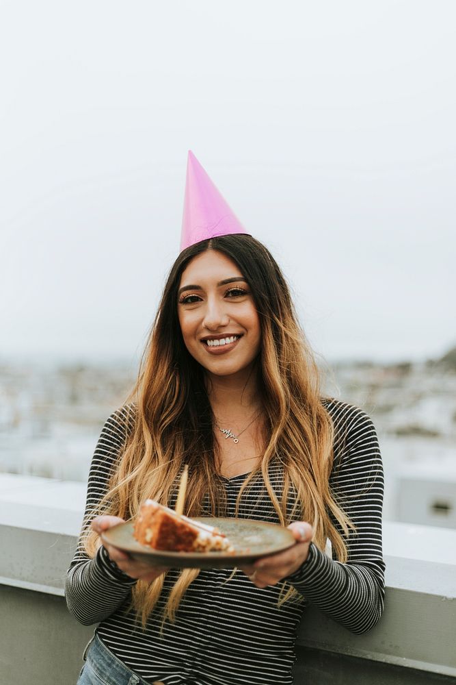 Woman with a party hat celebrating her birthday at a rooftop