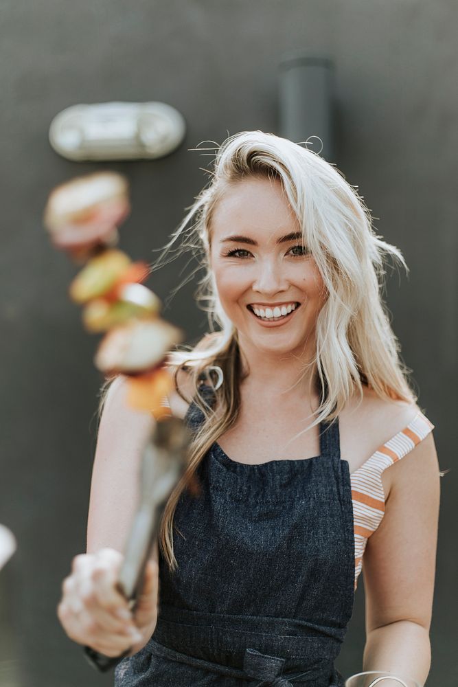 Cheerful woman cooking a barbeque skewer