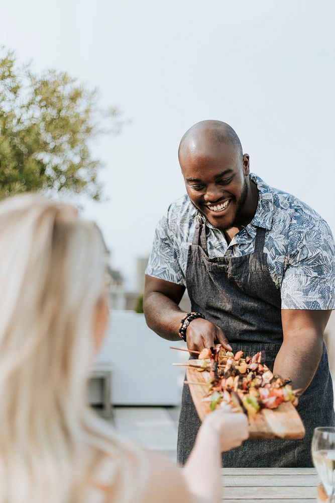 Cheerful chef serving grilled vegan barbeque skewers