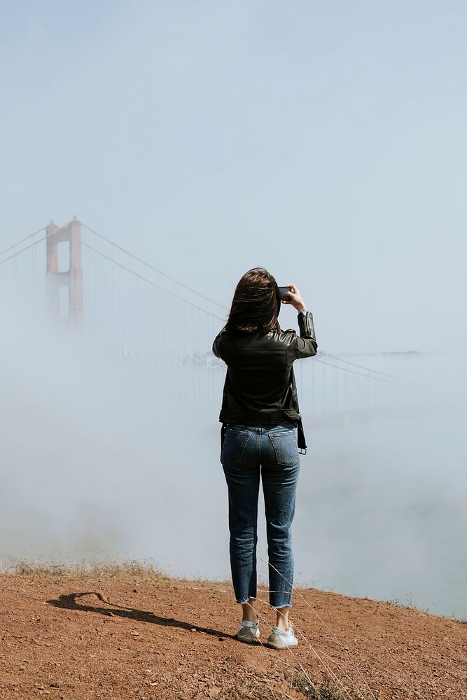 Woman taking a photo of the Golden Gate Bridge, San Francisco