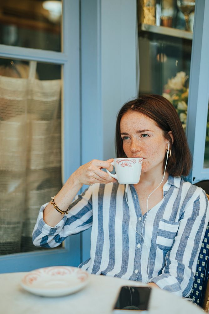 Woman drinking coffee and listening music from her phone