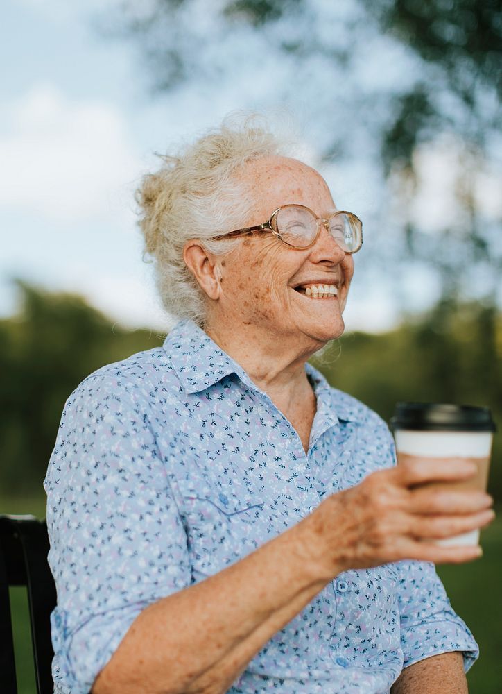 Happy senior woman having a takeaway coffee at the park