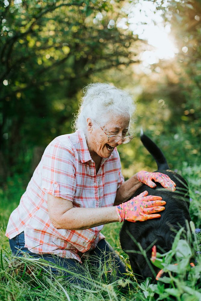 Senior woman petting her dog in the garden