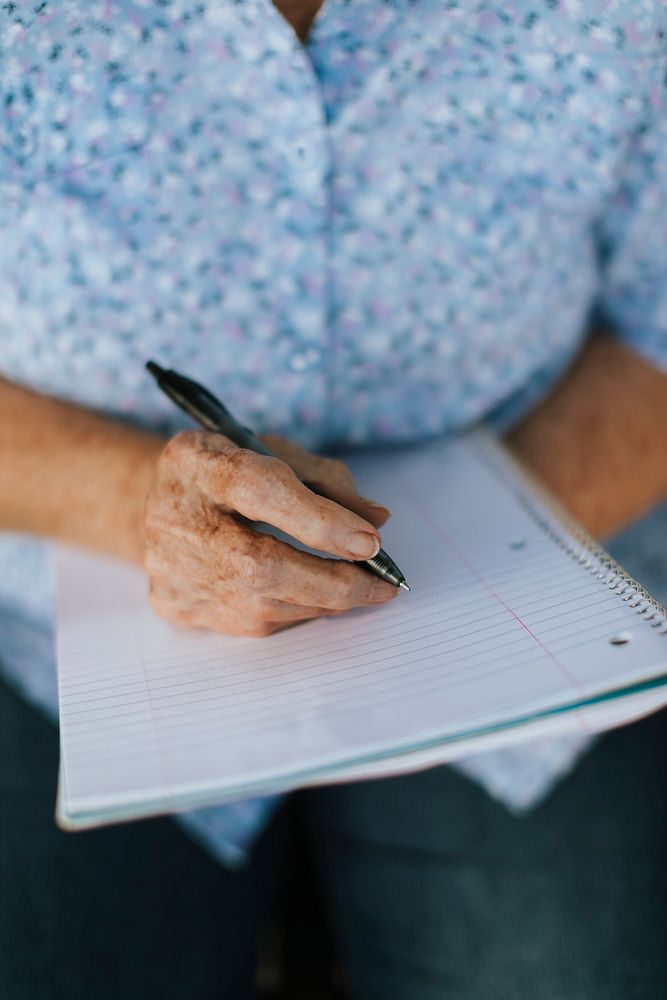 Senior woman writing down her memories into a notebook