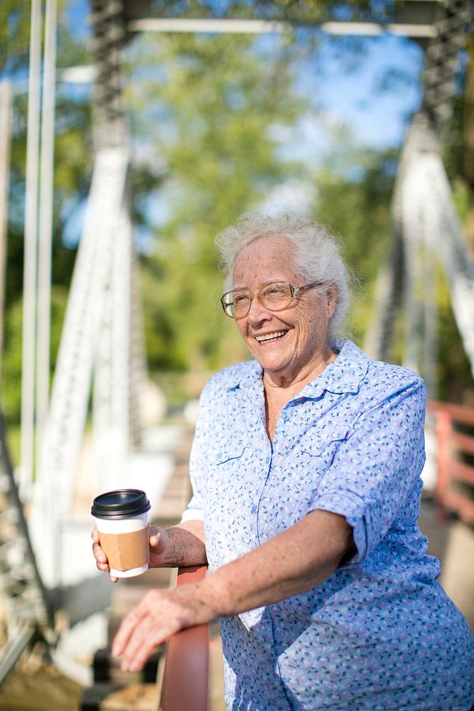 Senior woman standing on a bridge with a coffee