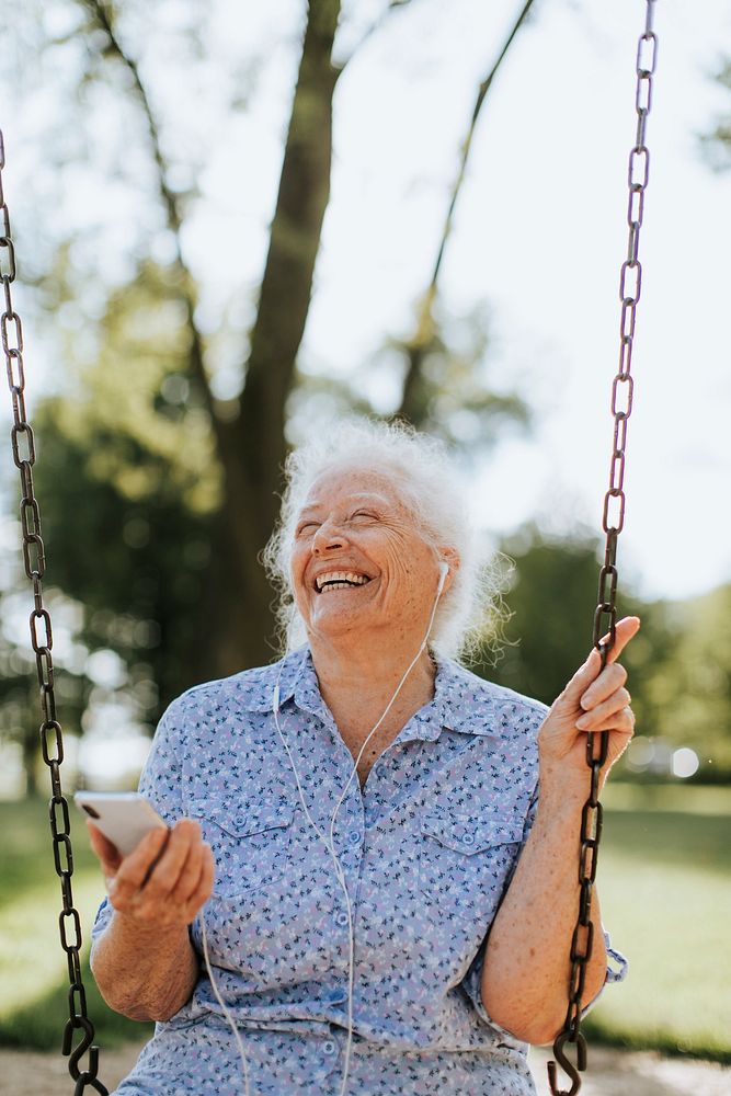 Cheerful senior woman listening to music at a playground