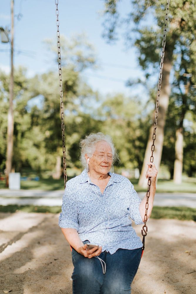 Happy senior woman listening to music on a swing