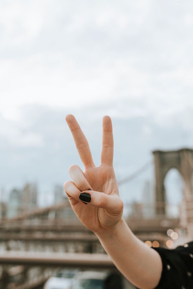 Woman showing a V sign at the Brooklyn Bridge, USA