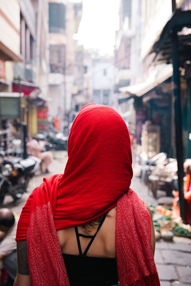 Western woman covered in a red scarf exploring Varanasi