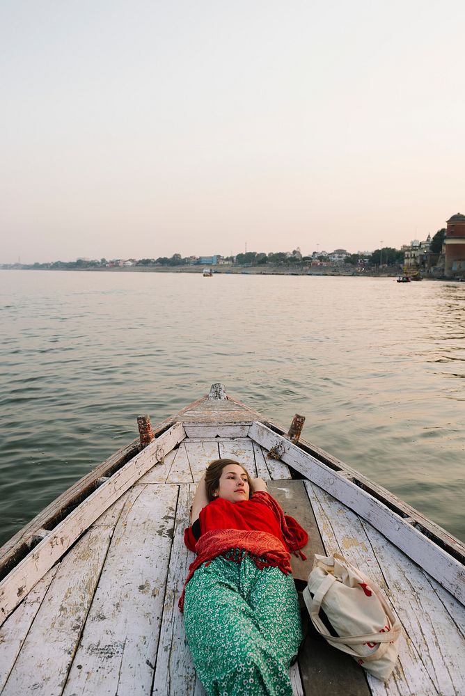 Western woman lying down on a boat on the River Ganges