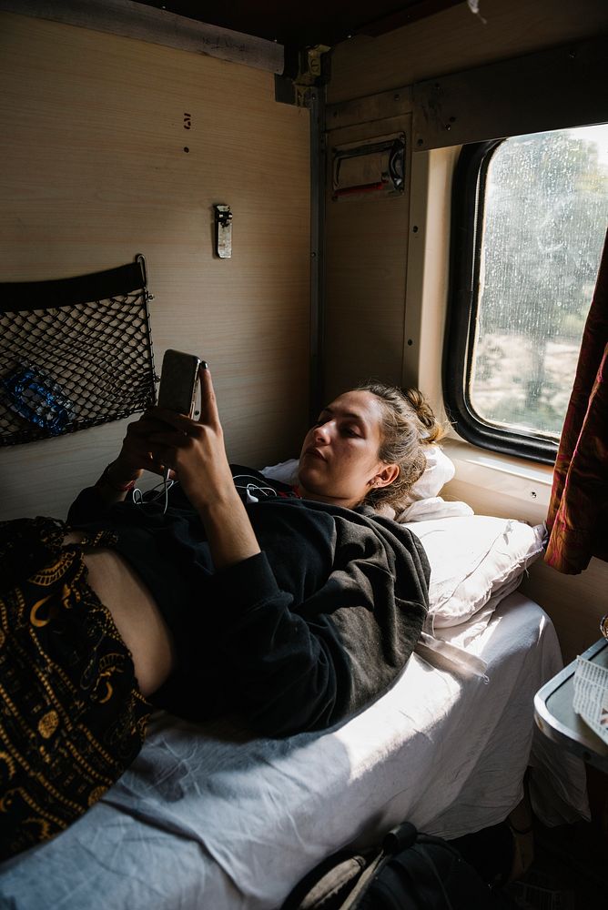Western female backpacker using her phone in the Indian train