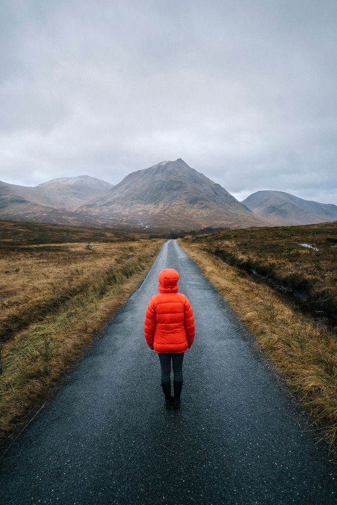 Woman walking on a road in Glen Etive, Scotland