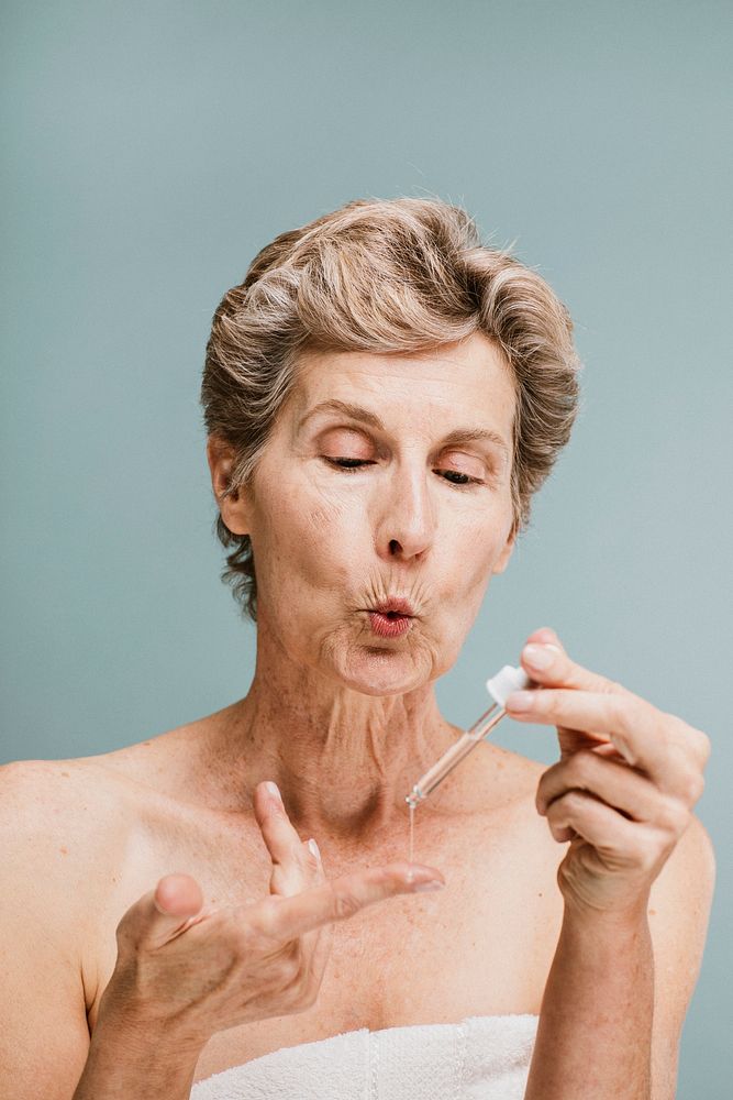Senior woman applying moisturizer on her fingertips