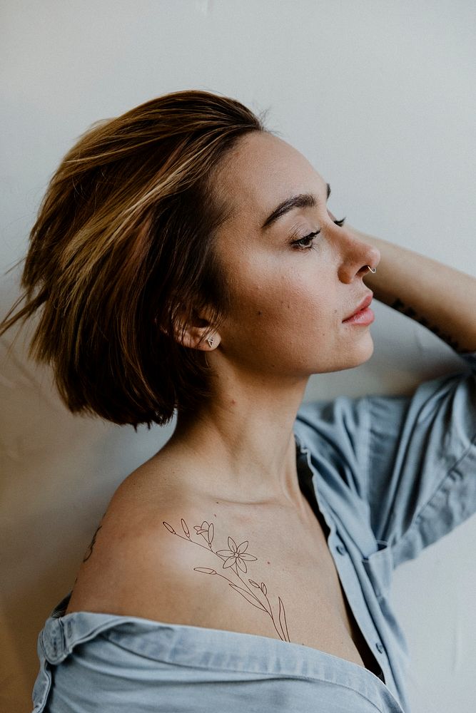 Portrait of a short hair woman with an expedition tattoo on her shoulder side view
