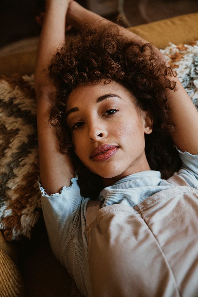 Closeup of a woman lying on a mustard yellow couch