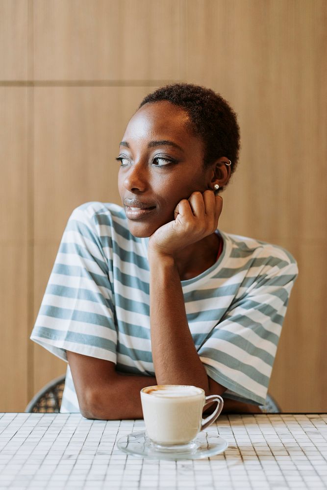 Black woman sitting thoughtfully in a cafe