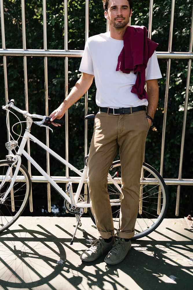 Handsome man standing by bicycle at street