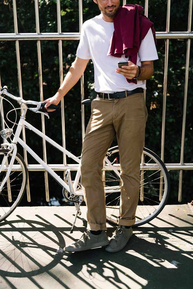 Caucasian man standing by bicycle and using moblie phone