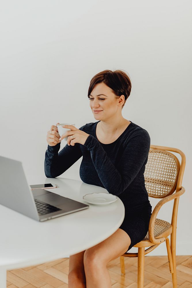 Positive woman with a cup of tea telecommuting