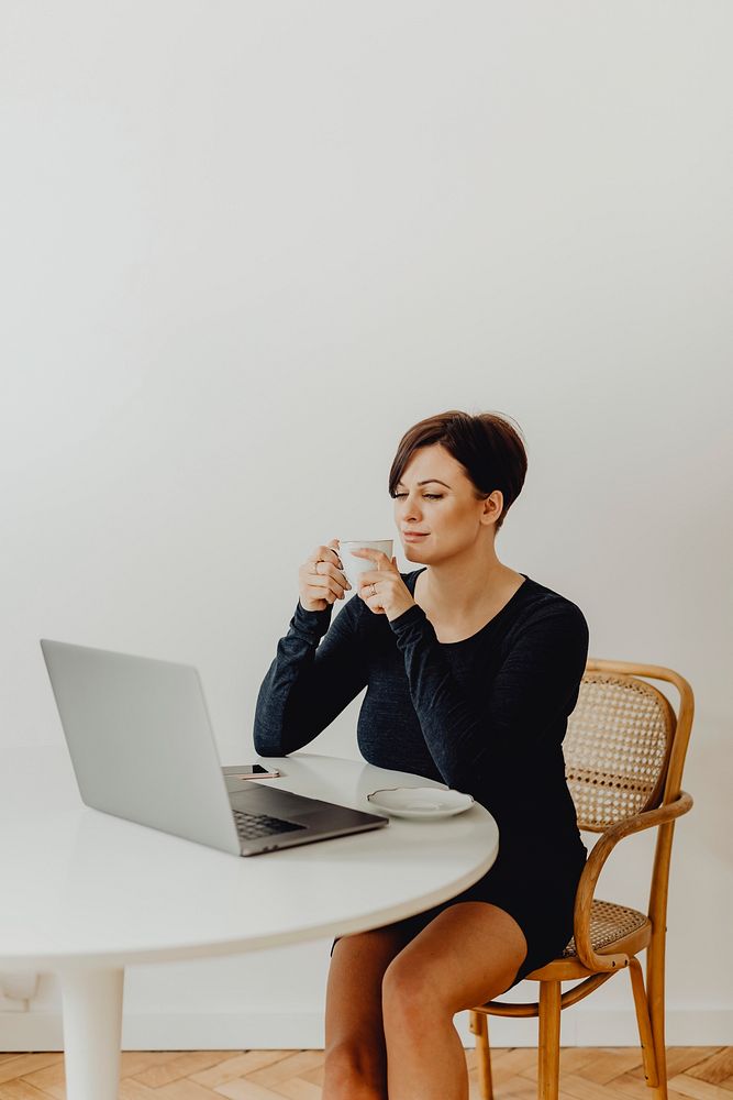 Positive woman with a cup of tea telecommuting