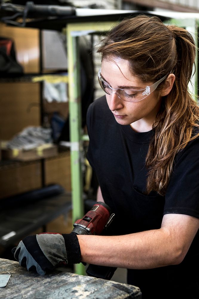 Female mechanic drilling into metal