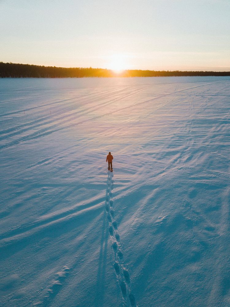 Man walking on the snow while admiring the sunset