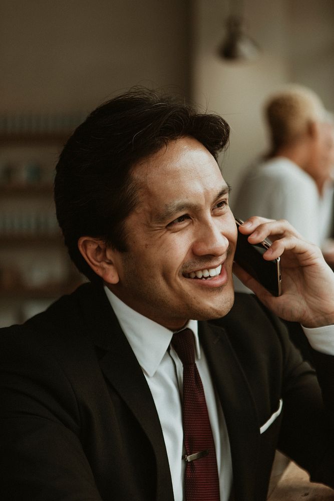 Happy businessman on the phone in a cafe
