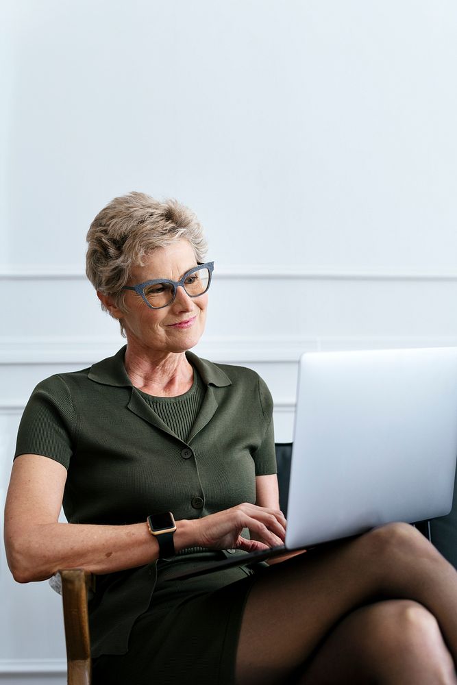Cheerful short blond-haired businesswoman using a laptop