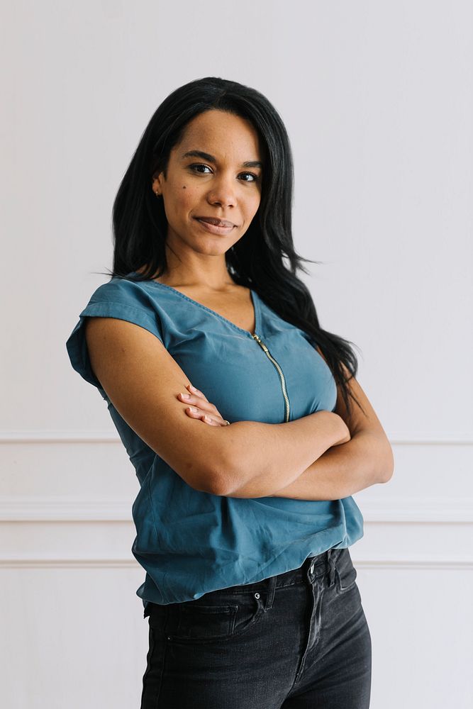 Happy empowering black woman standing by a white wall