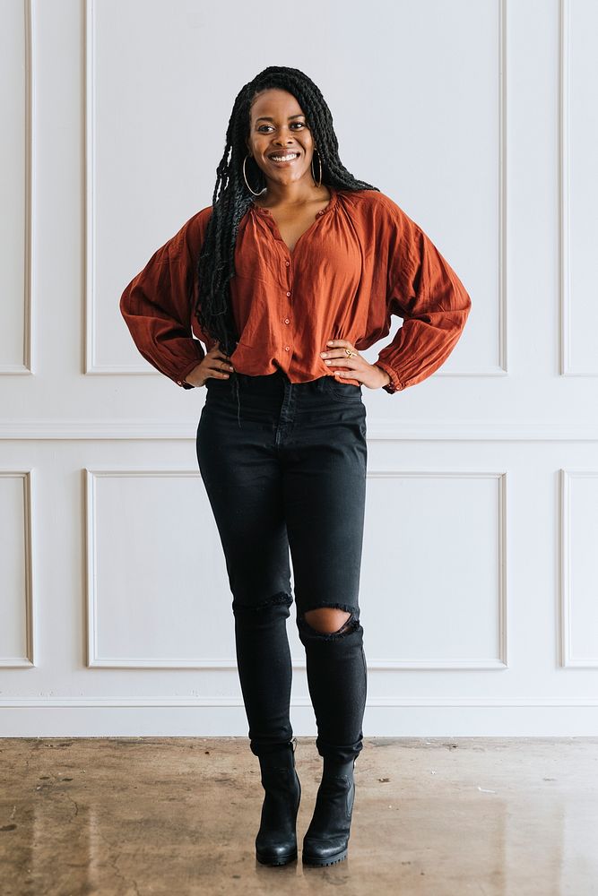 Happy empowering black woman standing by a white wall