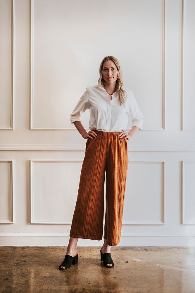 Fashionable woman standing by a white wall