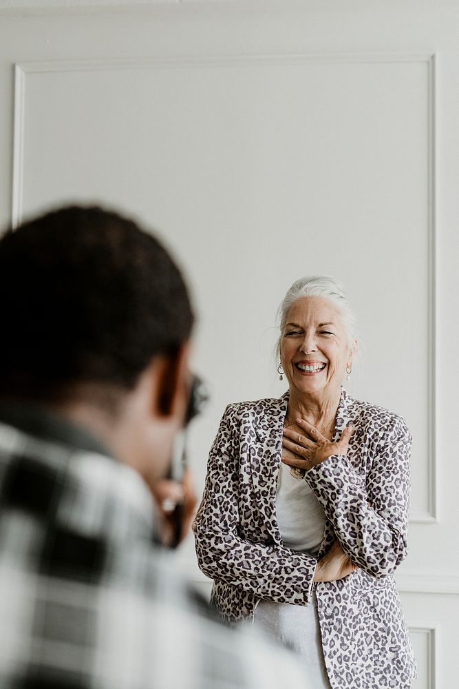 Black photographer taking a photo of a cheerful senior woman