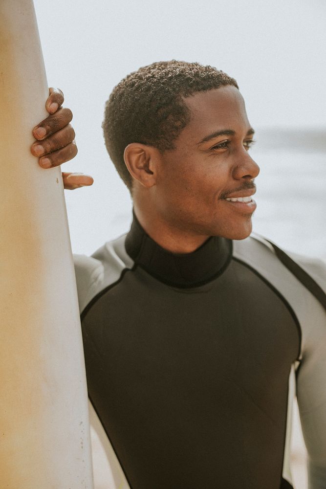 Black man standing by the surfboard
