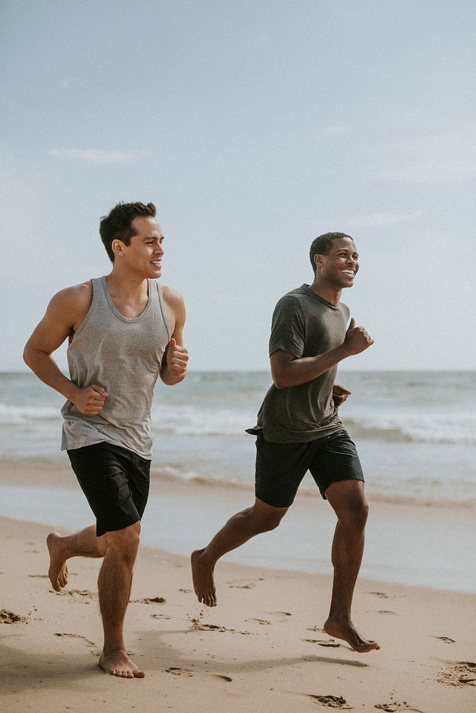 Happy friends jogging at the beach together