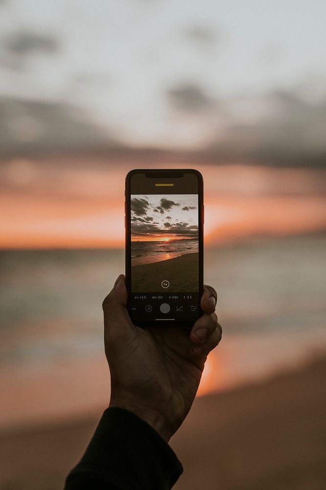 Man taking a picture of the sunset on the beach