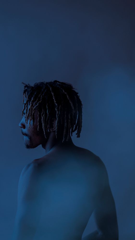 Black man posing by a blue background