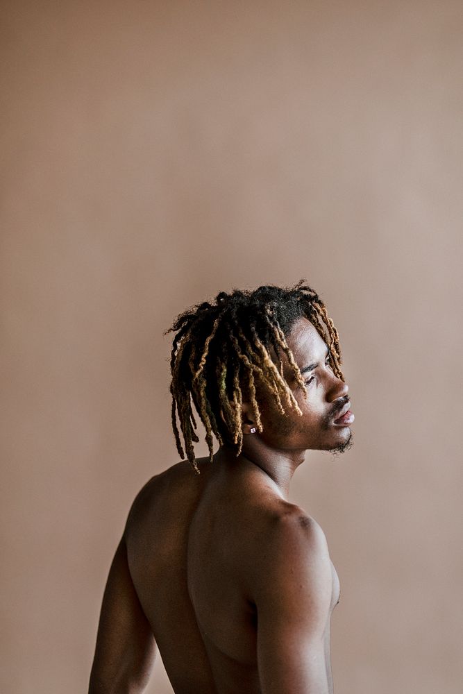 Black man posing by a beige background