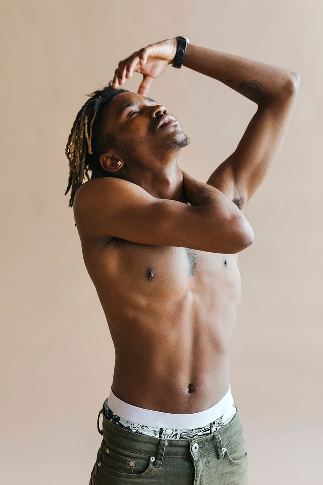 Black man stretching by a beige background