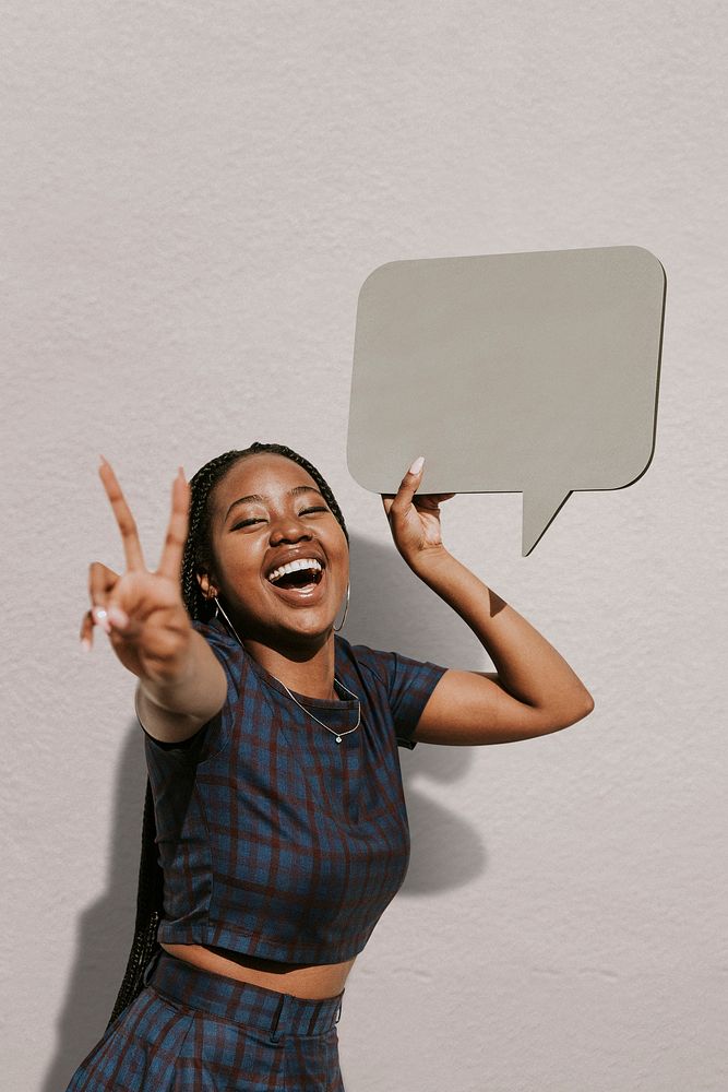 Cheerful black woman showing a v sign with a blank speech bubble