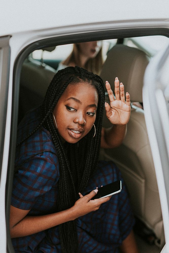 Black woman waving goodbye from a car