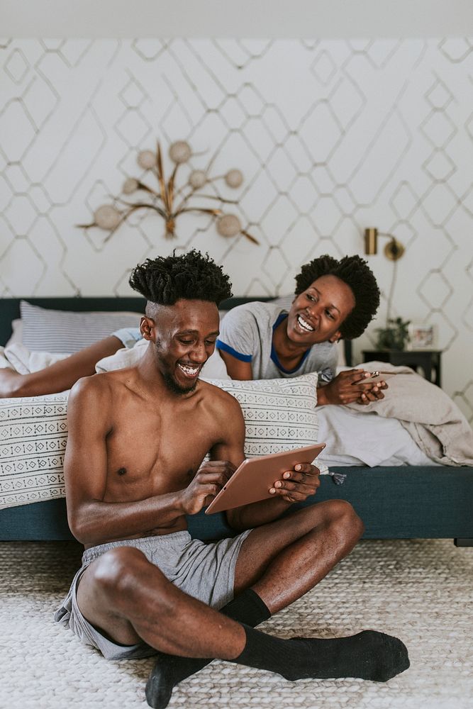 Cheerful black couple using digital devices