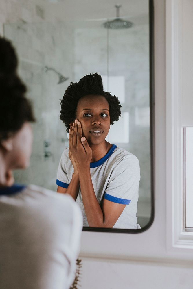 African woman standing by the mirror in the bathroom