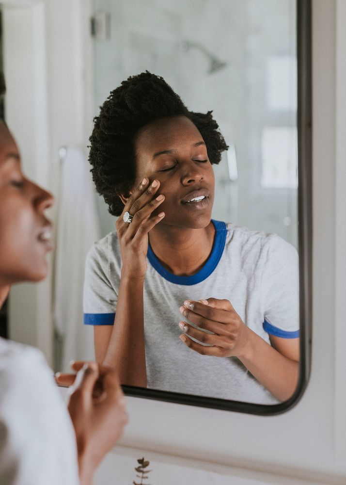 African woman standing by the mirror in the bathroom